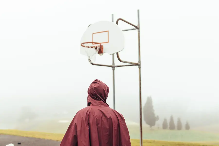 Freiluft-Basketballfeld im Nebel, eine Person von hinten