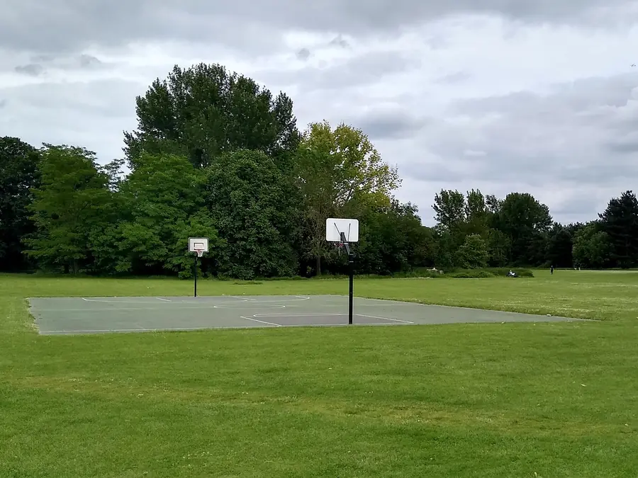 Freiluft-Basketballfeld zwischen Wiese und B&auml;umen